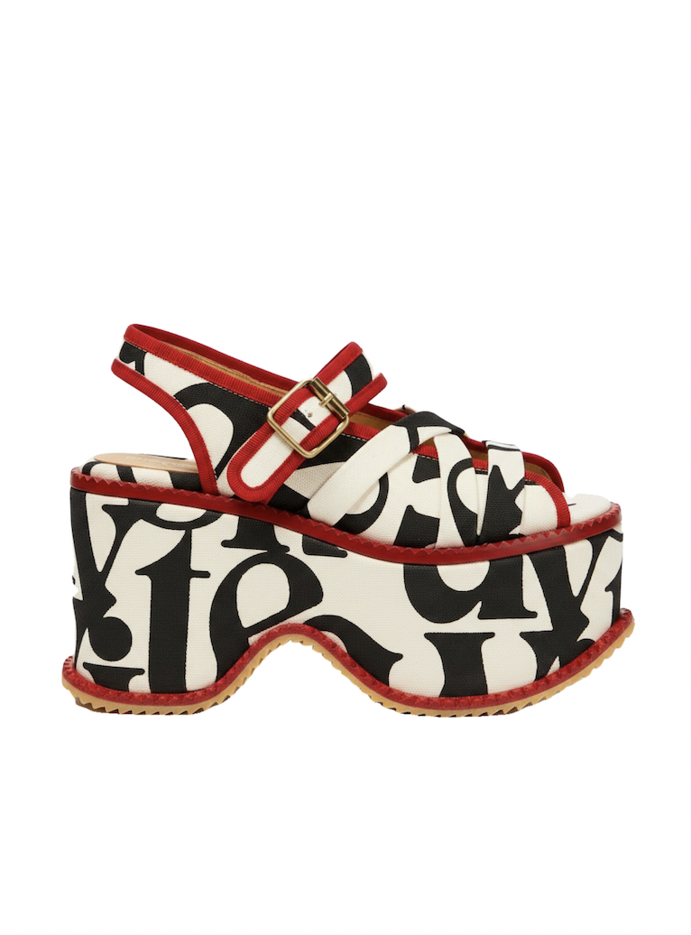 Bold red, black, and cream platform sandal with abstract lettering, buckled ankle straps, chunky wedge sole, and retro fashion style.